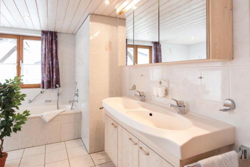 a bathroom with a sink and a tub and a mirror at Landhaus Tannheimer in Oberstdorf