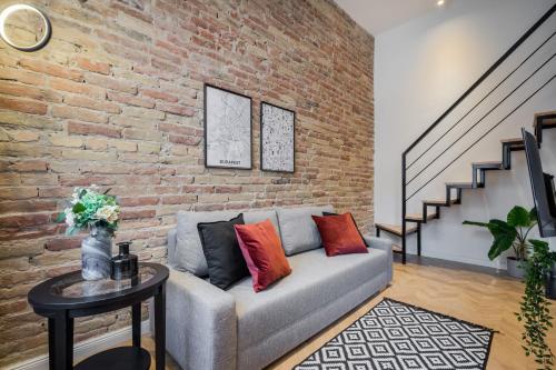 a living room with a couch and a brick wall at K33- Boutique Apartments, Best Location, by BQA in Budapest