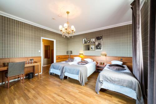 a hotel room with two beds and a desk at Stadshotellet Lidköping in Lidköping
