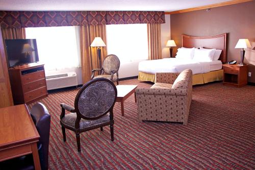 a hotel room with a bed and a couch and chairs at Holiday Inn Express Hotel & Suites Pierre-Fort Pierre by IHG in Fort Pierre