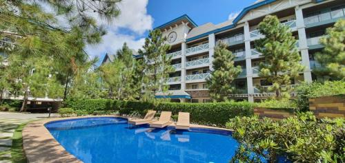 a hotel with a swimming pool and a building at Summer10th Pinesuites Scandi Minimalist Deluxe in Tagaytay