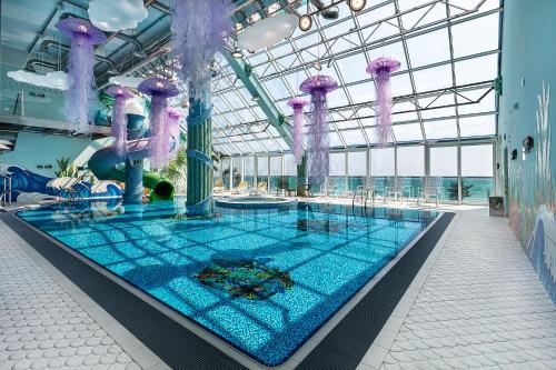 a large swimming pool in a building with purple decorations at UnderSun Spa Hotel in Gribovka