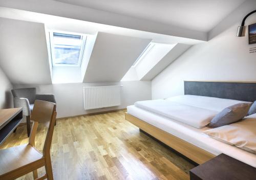 a bedroom with a bed and a desk and windows at JUFA Hotel Schladming in Schladming