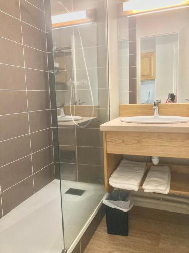 een badkamer met een wastafel en een glazen douche bij Résidence LE BEC DE L'AIGLE in Le Lioran