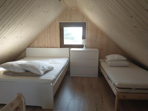 グダニスクにあるDomek na Wyspie Sobieszewskiejの屋根裏のベッドルーム(ベッド2台、窓付)