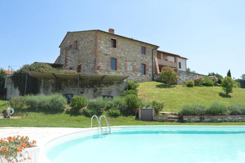 uma grande casa de pedra com uma piscina em frente em Holiday apartment with swimming pool, strade bianche, swimming pool, view em Pievina