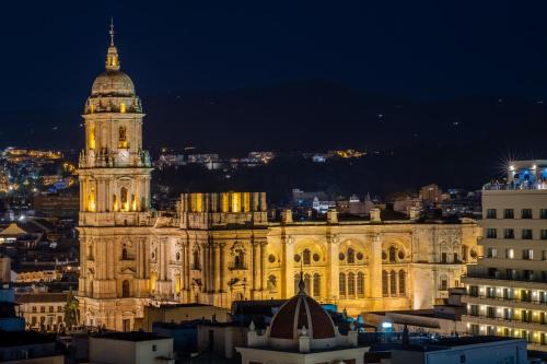 a large building with a clock tower at night at Soho Boutique Equitativa in Málaga