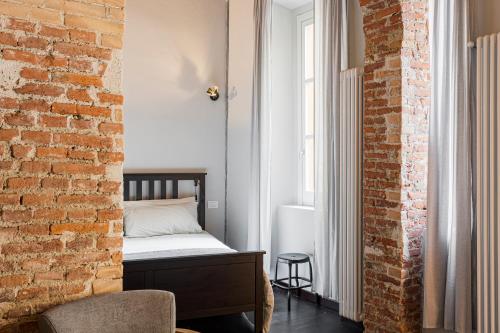 ein Schlafzimmer mit einem Bett und einer Ziegelwand in der Unterkunft Stylish Milanese Studio - Cirillo in Mailand