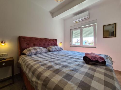 sypialnia z łóżkiem z kratkowaną narzutą i oknem w obiekcie House Plavi 2130 w Medulinie