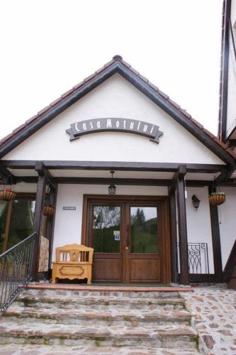 a building with a wooden door with a sign on it at Pensiunea Casa Motului in Arieşeni