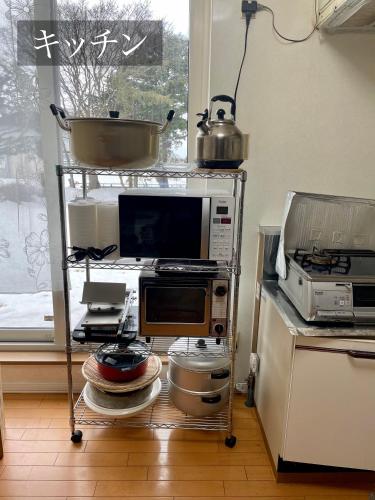 a kitchen with a microwave oven and a stove at 華明の宿 in Ebetsu