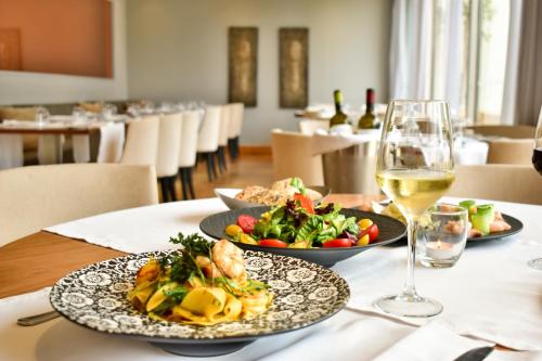 un tavolo con due piatti di cibo e un bicchiere di vino di Plaza Resort ad Anávissos