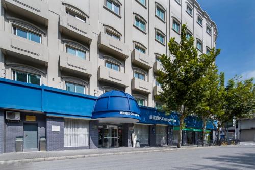an apartment building on a street with a blue awning at Campanile Shanghai Bund Hotel in Shanghai