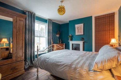 um quarto com paredes azuis, uma cama e uma janela em Lovely Central Cambridge Home em Cambridge
