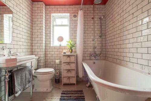 a bathroom with a tub and a toilet and a sink at Lovely Central Cambridge Home in Cambridge