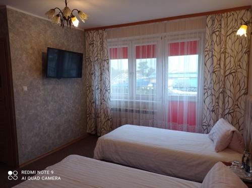 a hotel room with two beds and a window at Zajazd nad Sanem in Jarosław