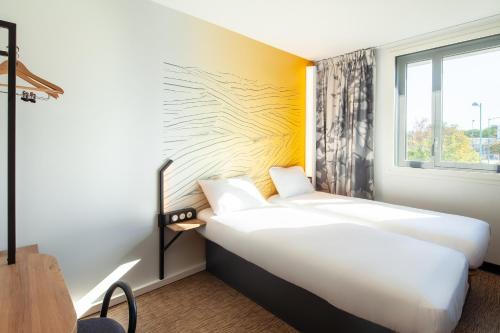 a hotel room with two beds and a window at B&B HOTEL Bois d'Arcy Saint Quentin en Yvelines in Bois-dʼArcy