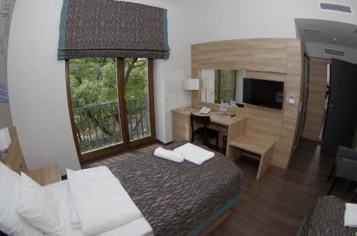 a hotel room with a bed and a desk and a television at Hotel Therapia in Pécs