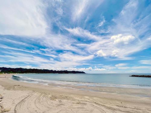 a beach with a cloudy sky and the ocean at Seaside SHELL HOUSE -南房総 海辺のSHELL HOUSE- in Minamiboso