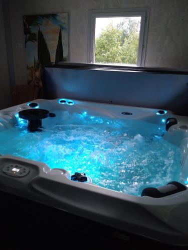 La salle de bains est pourvue d'une grande baignoire avec de l'eau bleue. dans l'établissement Gite Spa Détente Nature L'Estompe, à Fresse