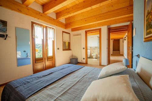 Un dormitorio con una cama grande en una habitación con techos de madera. en Agriturismo La Cascina B&B en San Fedele Intelvi