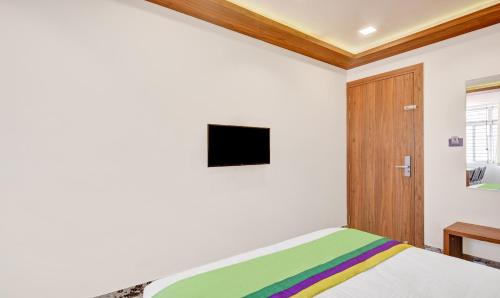 a bedroom with a bed and a tv on the wall at Itsy Hotels Shrey'S Inn Mallandur Road in Chikmagalūr