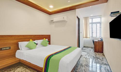 a bedroom with a bed and a flat screen tv at Itsy Hotels Shrey'S Inn Mallandur Road in Chikmagalūr