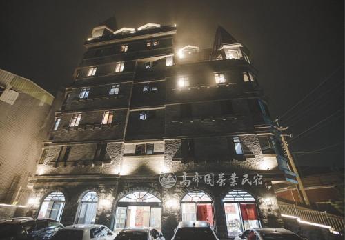 a tall building with cars parked in front of it at Gaodiyuan Tea B&B 高帝園茶業民宿 in Meishan