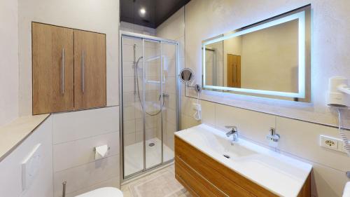 La salle de bains est pourvue d'un lavabo, d'une douche et d'un miroir. dans l'établissement Ferienwohnung am Saarweg, à Merzig