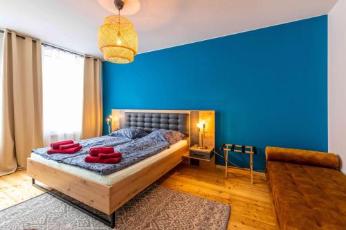 Großer Terrassentraum in Klein Venedig في لايبزيغ: غرفة نوم بجدران زرقاء وسرير بمخدات حمراء