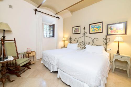 a white bedroom with two beds and a chair at Casa de los Bates in Motril