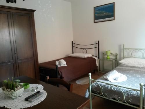a small room with two beds and a table with a tableablish at Affittacamere Le Statue Del Sinis in Càbras
