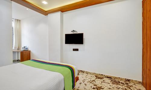 a bedroom with a bed and a tv on the wall at Itsy Hotels Shrey'S Inn Mallandur Road in Chikmagalūr