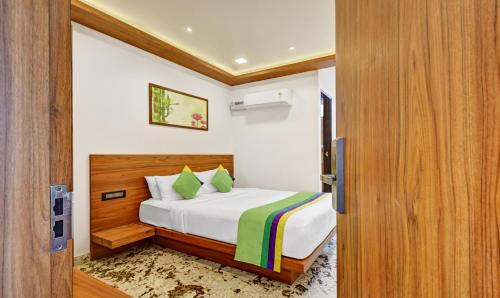 a bedroom with a bed and a wooden door at Itsy Hotels Shrey'S Inn Mallandur Road in Chikmagalūr