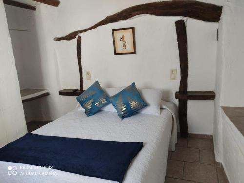 een slaapkamer met een bed met blauwe en witte kussens bij Azahar in Lecrin
