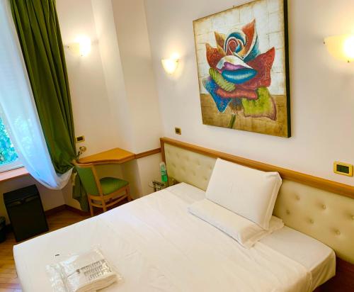 a bedroom with a white bed and a picture on the wall at Hotel Regina Margherita in Rome