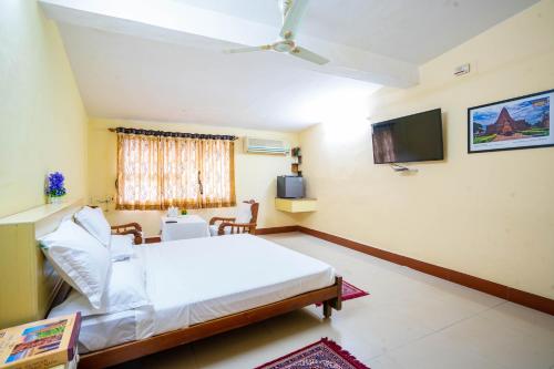 a bedroom with a white bed and a television at Hotel TamilNadu, Hosur in Hosūr