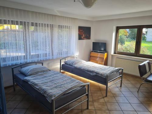 a bedroom with two beds and a dresser and window at Fifties Apartment Bechhofen in Bechhofen