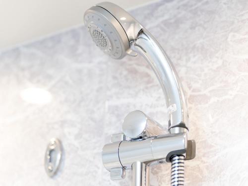 a chrome shower head on a bathroom sink at Hiyori Hotel Osaka Namba Station in Osaka