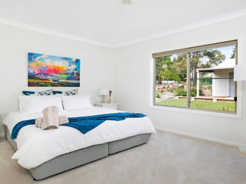 a white bedroom with a large bed and a window at Ballogie Lodge in Bundanoon