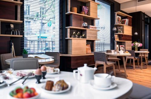 a dining room with a table with plates of food at Hotel Max in Paris