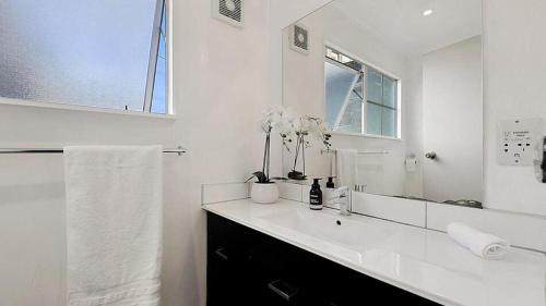 a white bathroom with a sink and a mirror at ULTIMATE CONVENIENCE, WALK-TO-TOWN TOWNHOUSE in Queenstown