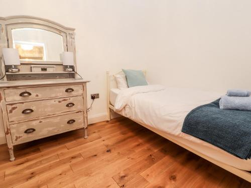 a bedroom with a bed and a dresser with a mirror at Glan Y Ddol in Trefriw