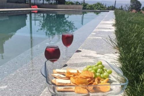 a plate of food and wine glasses next to a pool at CASA DA CASTANHEIRA in Candeiro