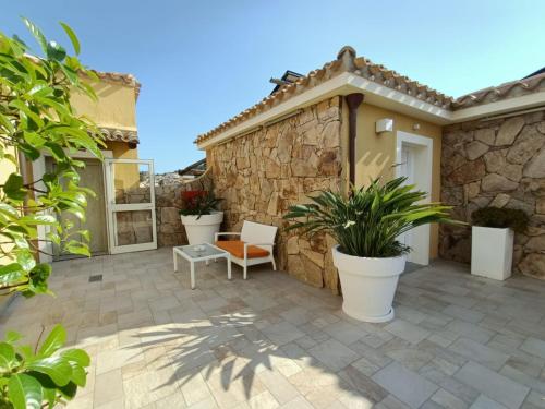 a patio with two chairs and a stone wall at Janas Hotel in Villasimius