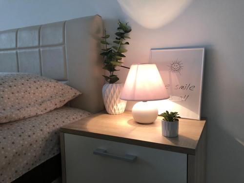 a lamp on a night stand next to a bed at Apartmani Tesla in Soko Banja