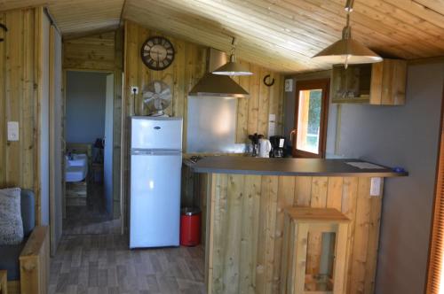 uma cozinha com um frigorífico branco numa casa de madeira em La Fontaine de la Chapinière CW em Châteauvieux