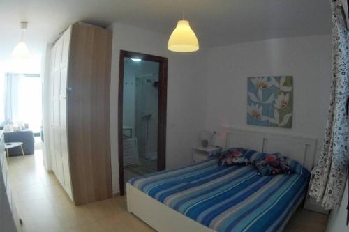 a bedroom with a bed with a blue striped blanket at CasaMandy CotilloMar in El Cotillo