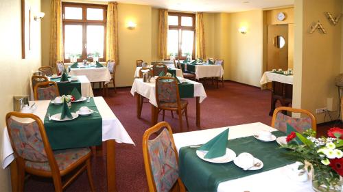 ein Esszimmer mit Tischen und grünen Tischdecken in der Unterkunft Hotel Garni Kluth in Bonn