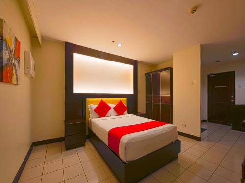 Schlafzimmer mit einem Bett mit roten Kissen und einem Fenster in der Unterkunft OYO 115 Northridge Mansions in Manila